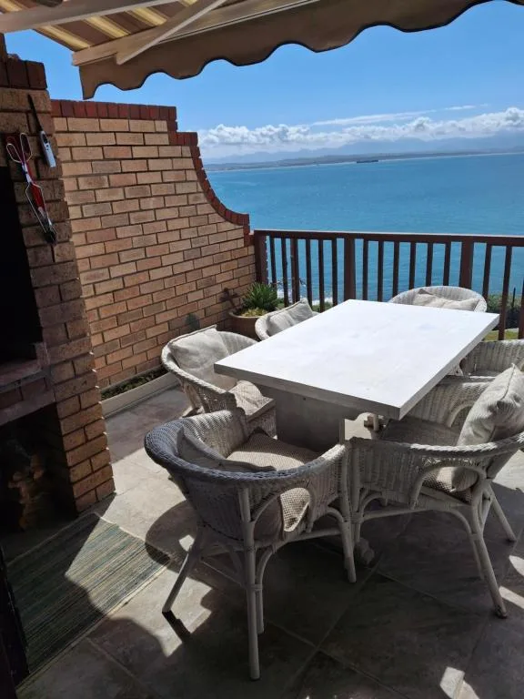Outdoor dining table with chairs on seaside balcony overlooking ocean