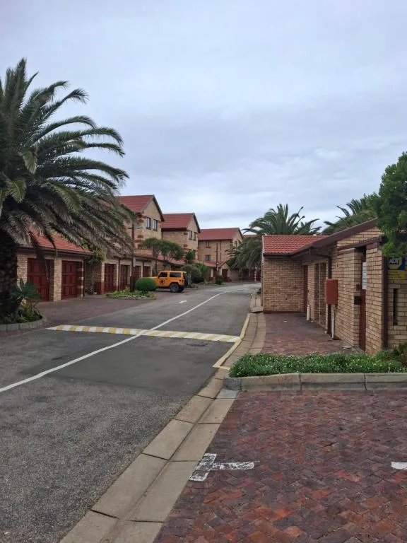 Brick townhouses with red tile roofs, palm trees, and paved driveway