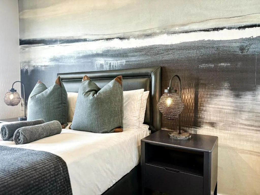 Modern bedroom with leather headboard, blue pillows, and lagoon view artwork