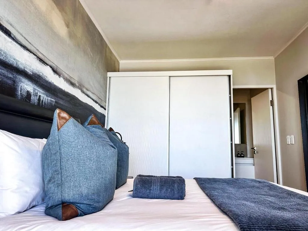 Modern bedroom with blue accent pillows and built-in wardrobe storage