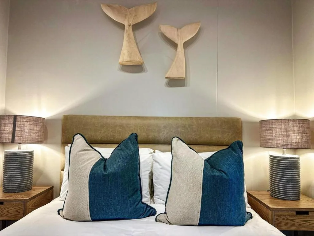 Modern bedroom with olive headboard, decorative whale tail wall art, patterned pillows