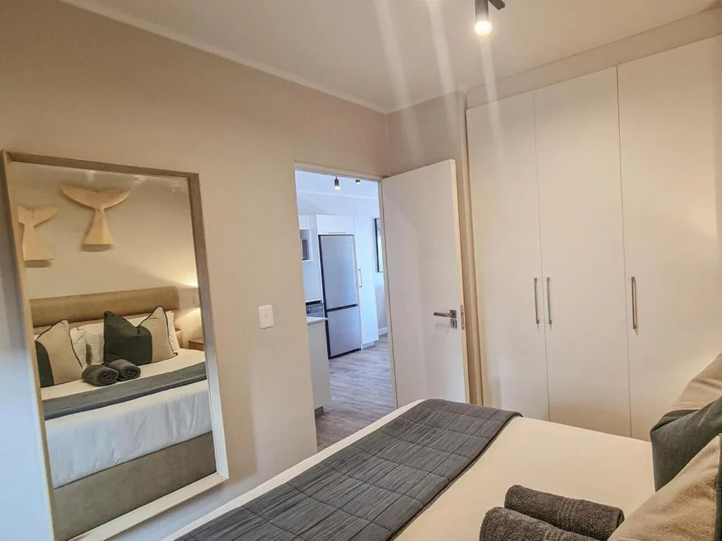 Modern bedroom with bed, mirror, and white built-in wardrobes