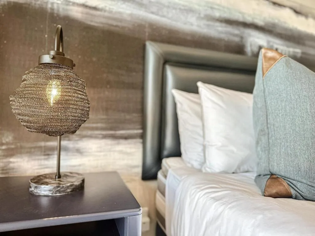 Modern bedroom with grey upholstered headboard and decorative woven table lamp