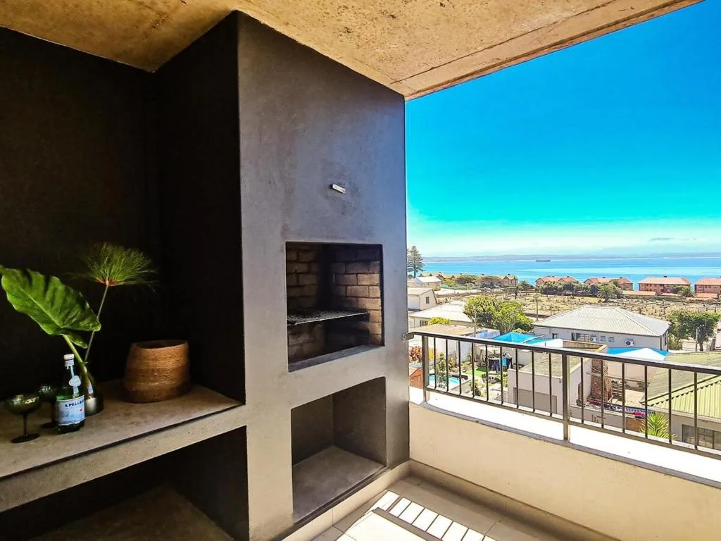 Modern outdoor deck with built-in fireplace and panoramic ocean views