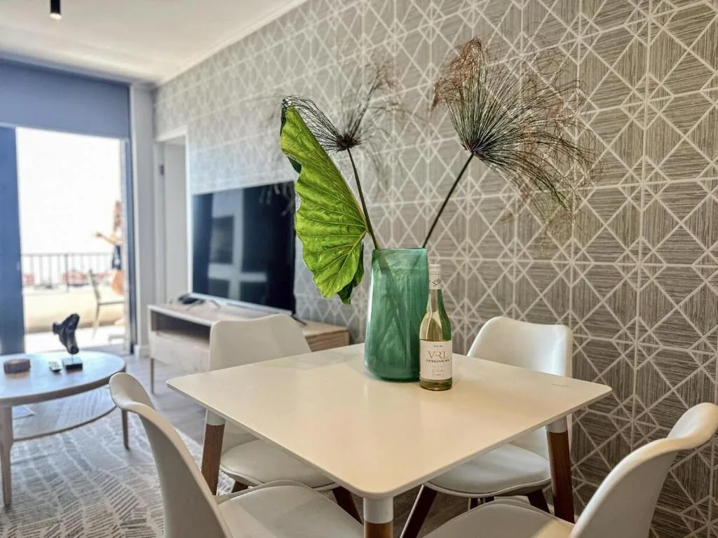 Modern dining table with white chairs and decorative floral centerpiece arrangement