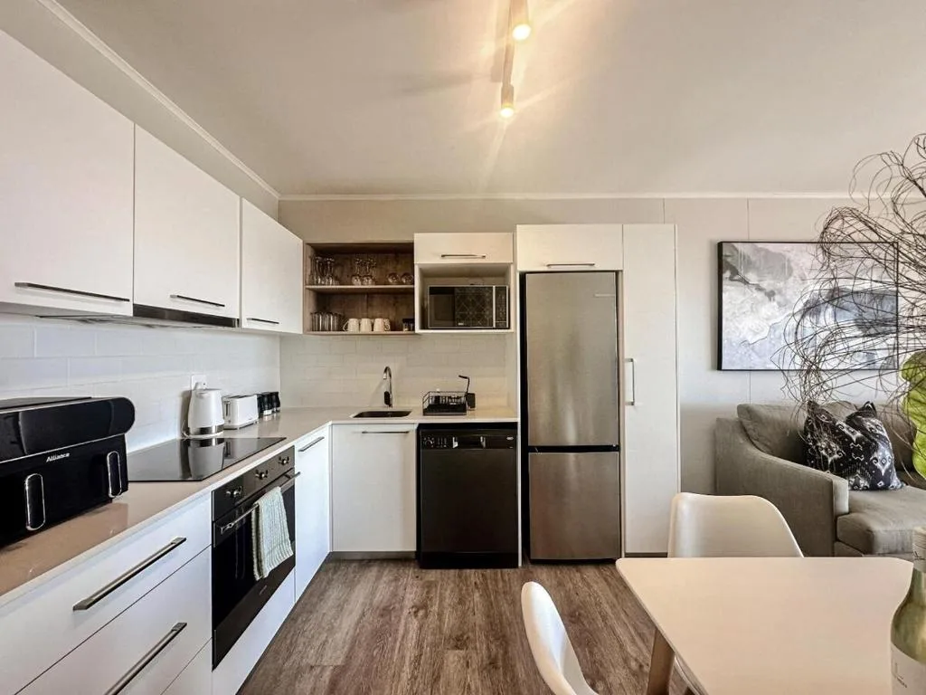 Modern kitchen with white cabinetry, stainless steel appliances, and wood flooring