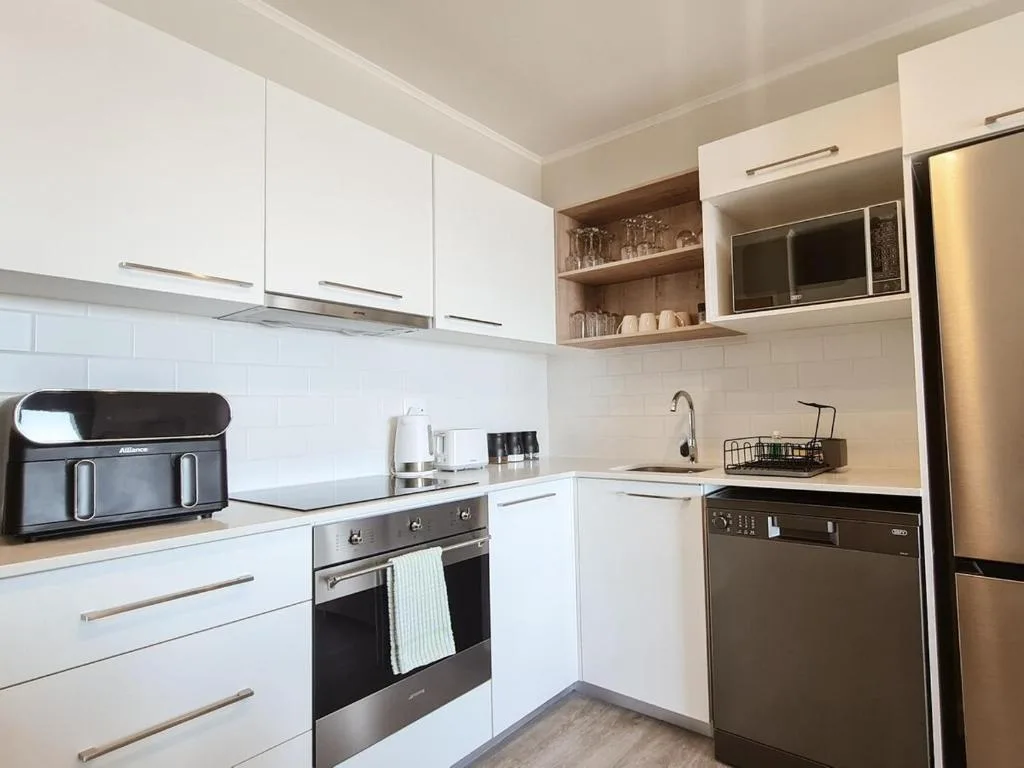 Modern kitchen with white cabinetry, stainless steel appliances, and open shelving