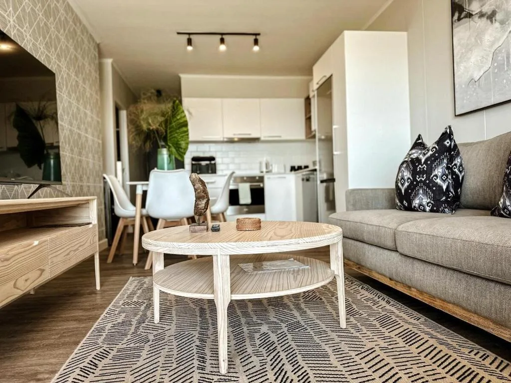 Modern lounge with gray sofa, round white coffee table, and open kitchen area