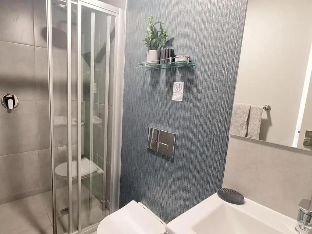 Modern bathroom with glass shower enclosure and textured tile walls