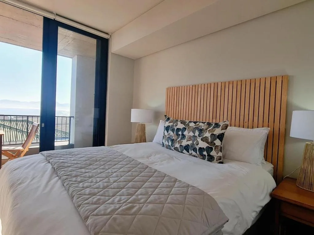 Spacious bedroom with wooden headboard, ocean view through glass doors