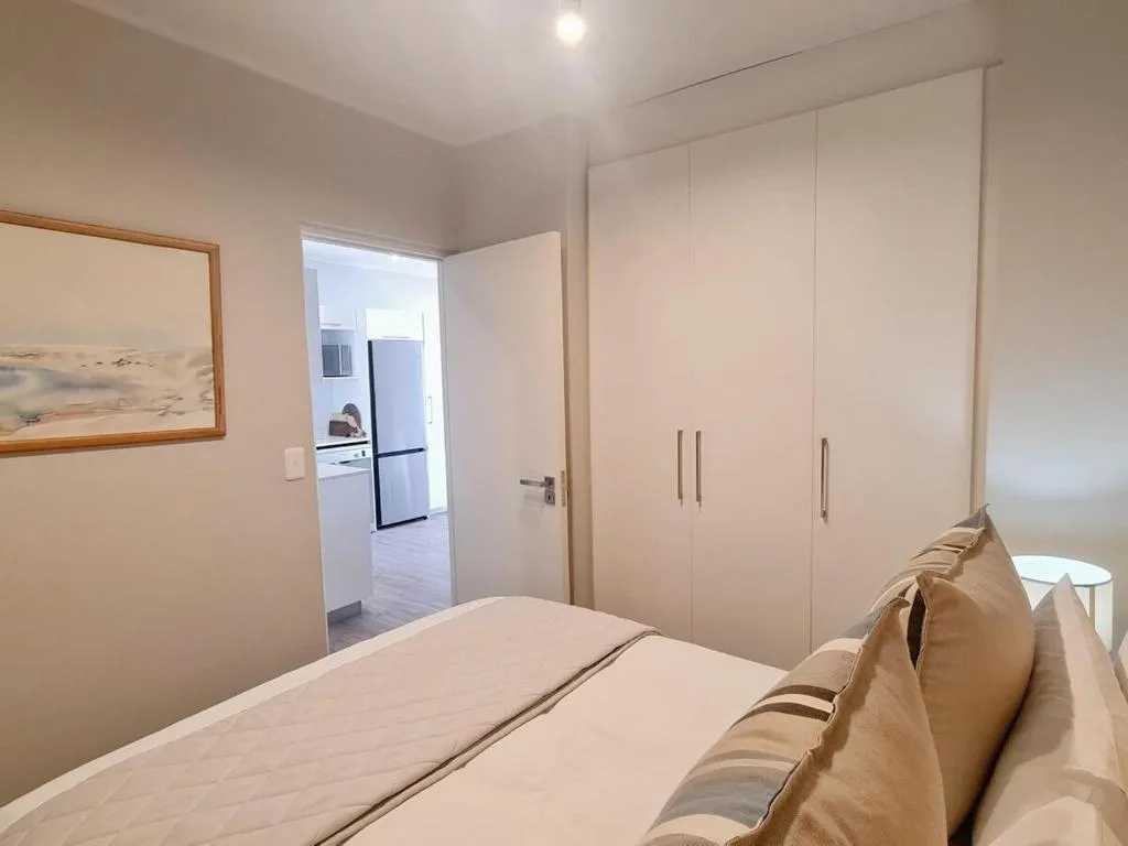 Spacious bedroom with double bed, built-in wardrobes, and kitchen view