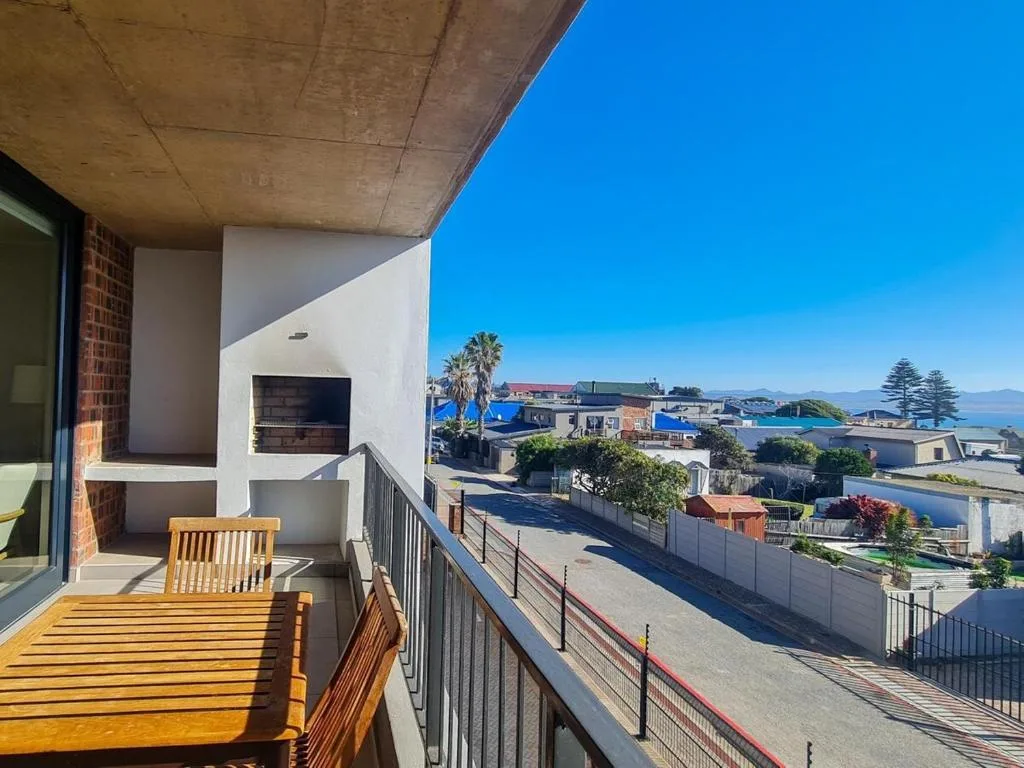 Wooden deck with chair overlooking coastal town and sea beyond