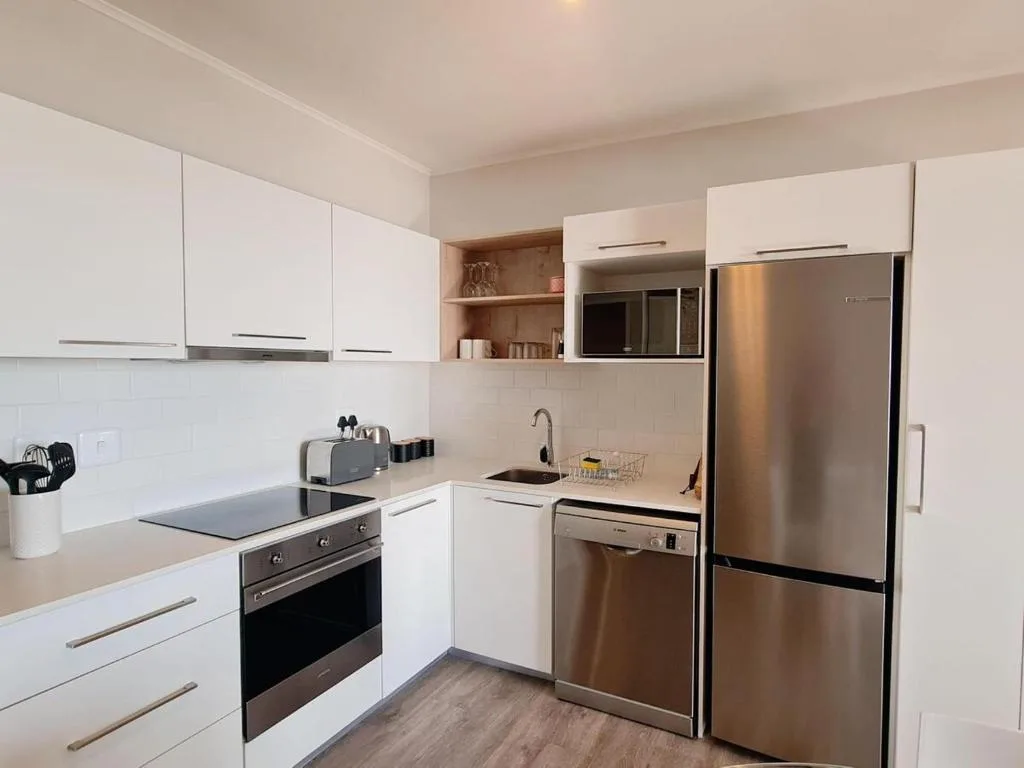 Modern white kitchen with stainless steel appliances and open shelving