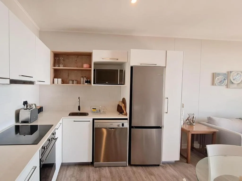 Modern kitchen with white cabinetry, stainless steel appliances, and open shelving