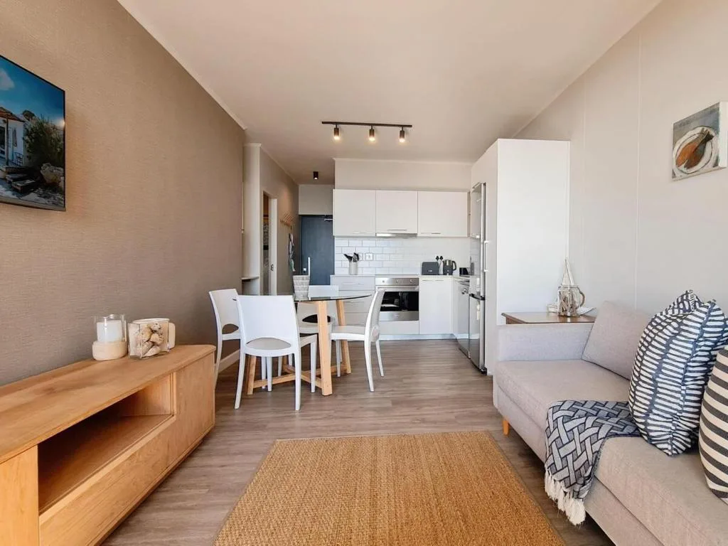 Open-plan lounge with sofa, dining area, and kitchen visible in background