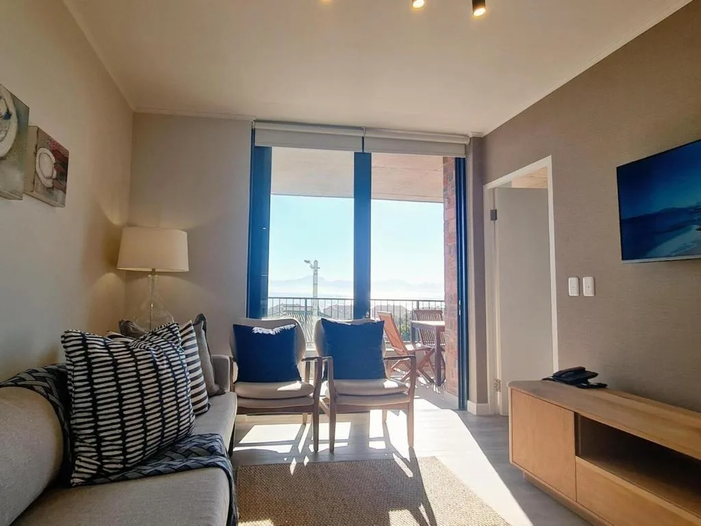 Bright lounge with sofa, ocean view through glass doors to deck