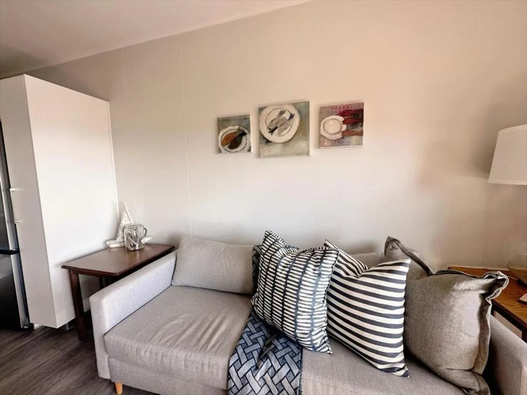 Modern lounge with gray sofa, striped pillows, small side table, and wall art