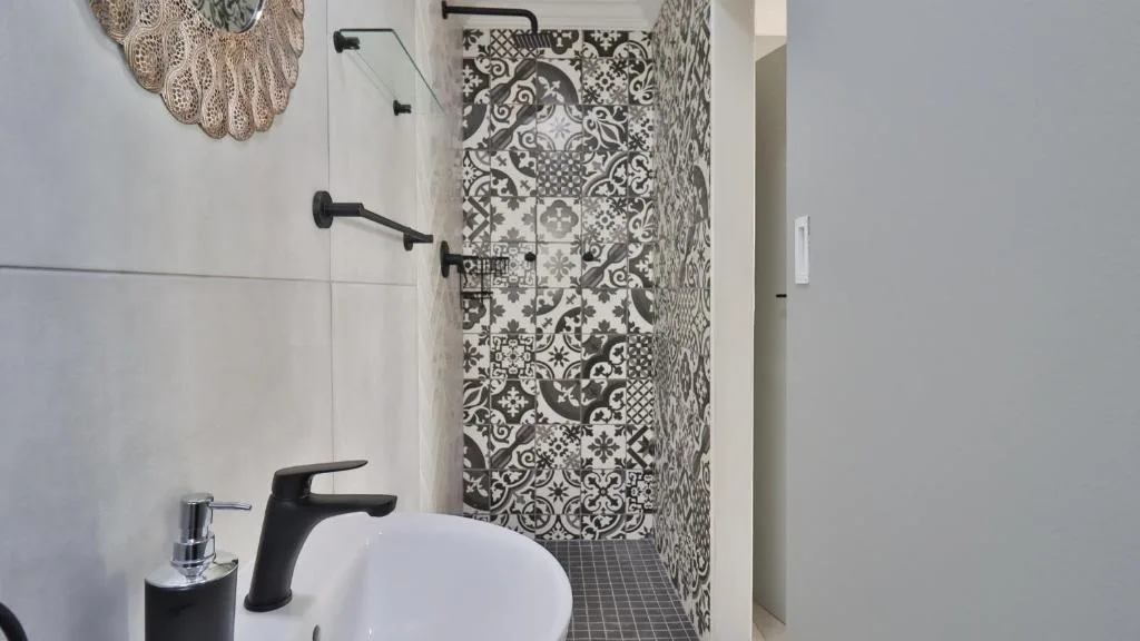 Modern bathroom with patterned tile shower wall and black fixtures