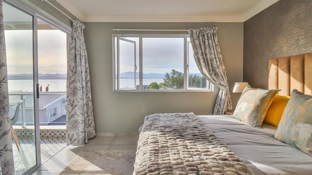 Bright bedroom with ocean view through windows and glass doors