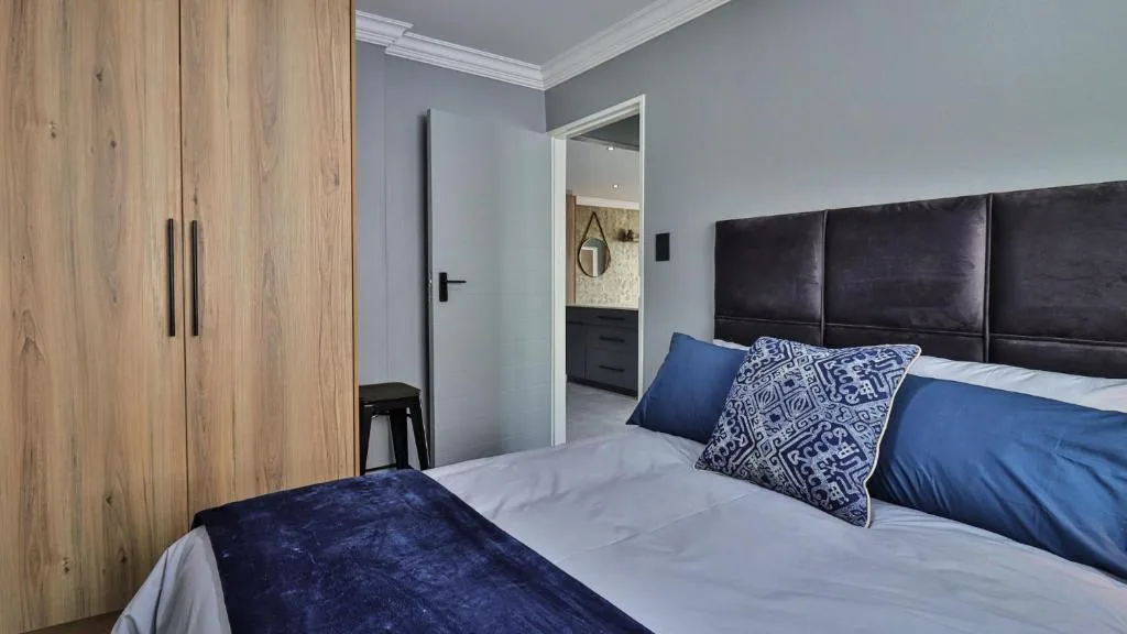 Modern bedroom with black headboard, blue bedding, and wooden wardrobe