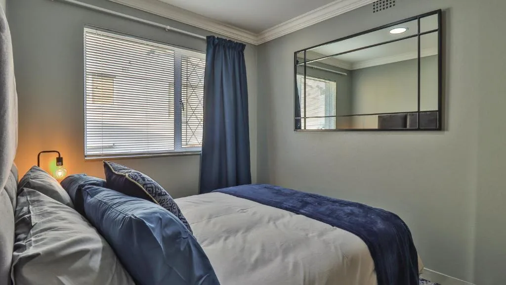 Modern bedroom with double bed, navy bedding, and large window with shutters