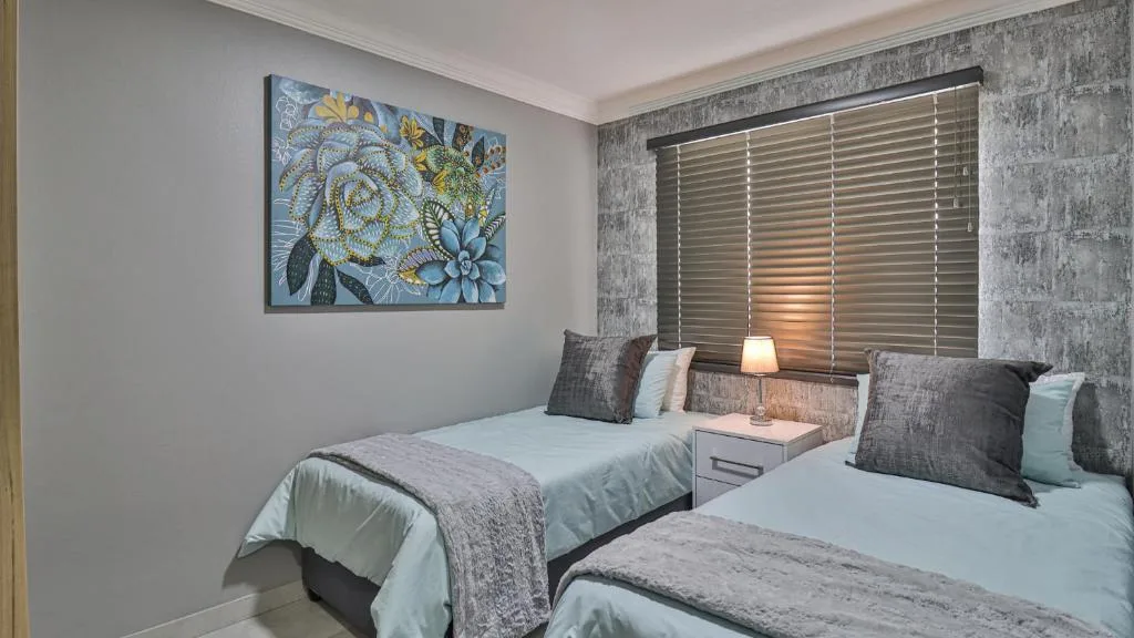 Twin bedroom with contemporary artwork, shuttered window, and neutral furnishings