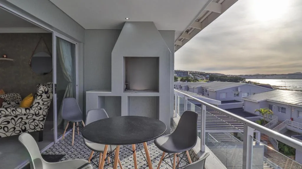 Modern balcony with dining table overlooking water and coastal town landscape