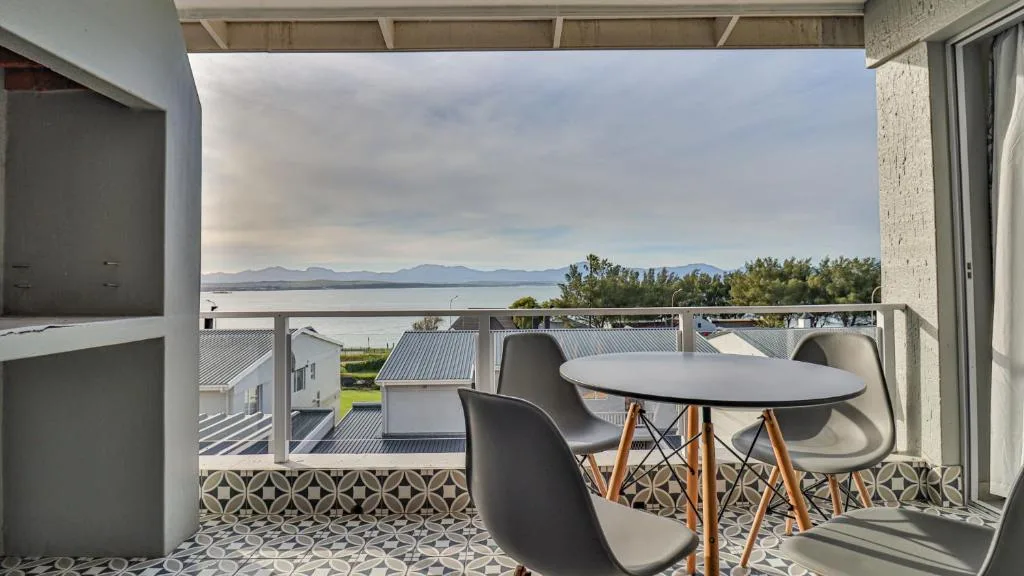 Covered balcony with dining table overlooking lagoon and mountains
