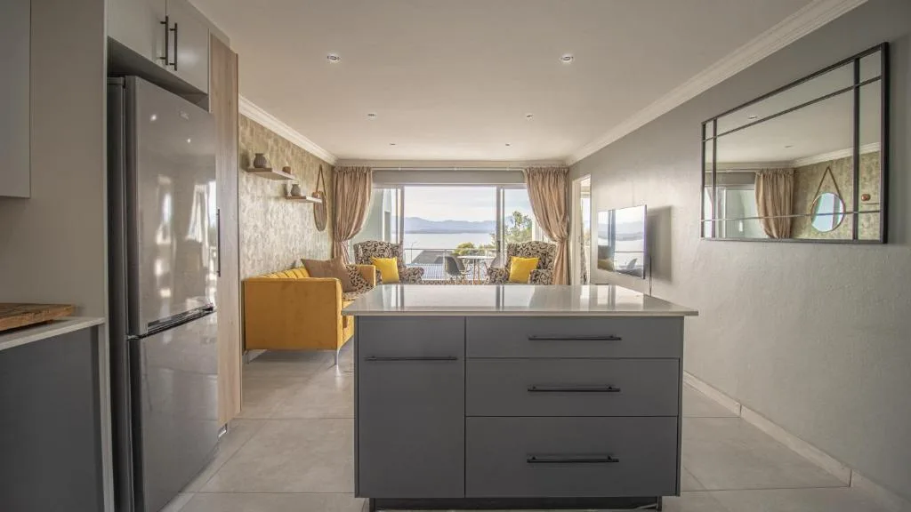 Modern kitchen with island counter, stainless appliances, ocean views beyond