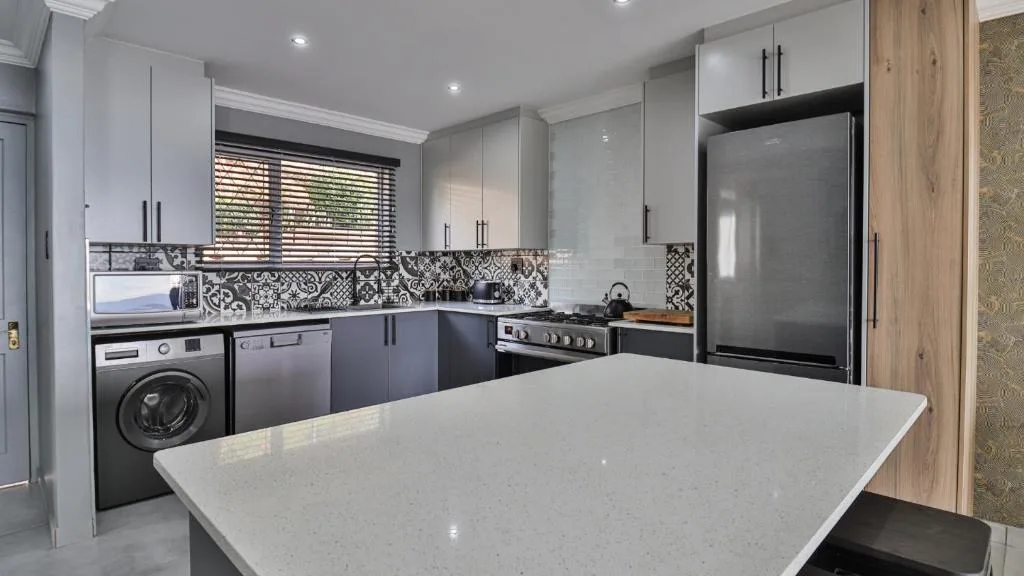 Modern kitchen with stainless steel appliances and patterned backtile