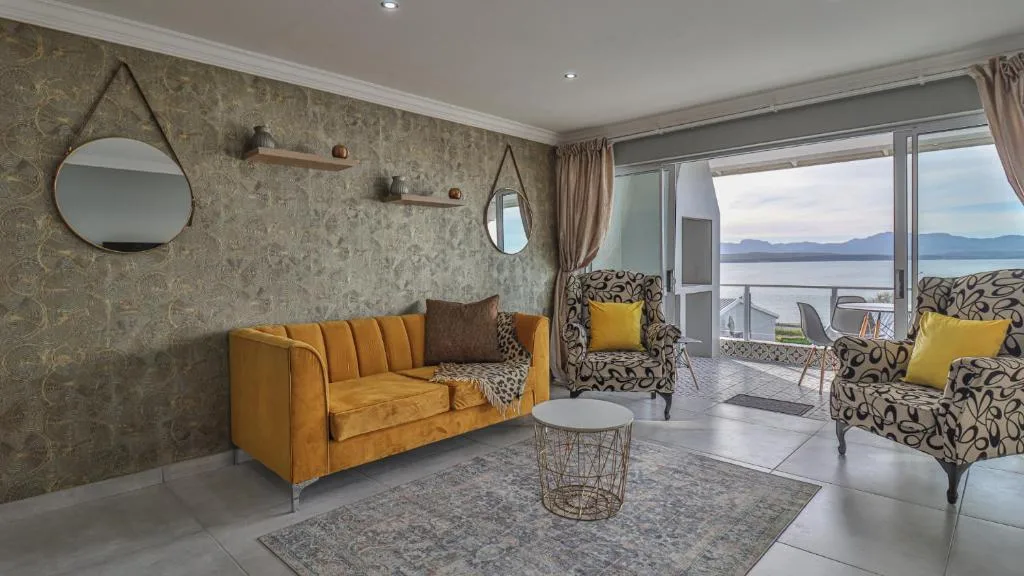 Stylish living room with gold sofa and patterned chairs overlooking lagoon views