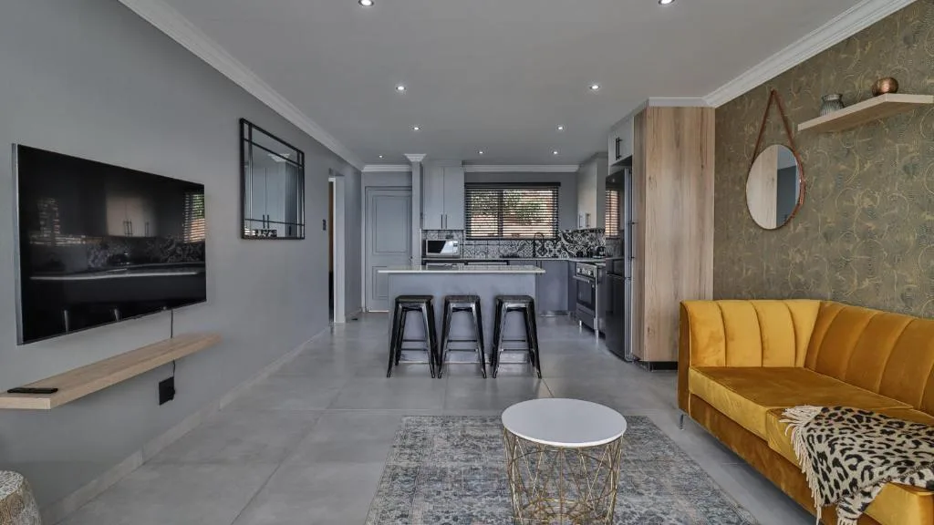 Modern lounge with yellow sofa, TV, and open-plan kitchen layout