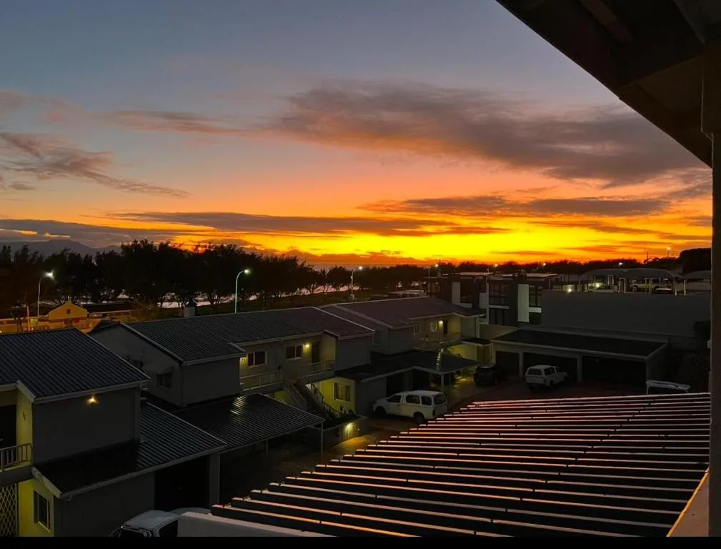 Golden sunset sky over Mossel Bay with residential buildings and distant lagoon