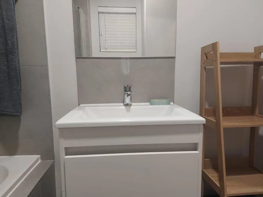 Modern bathroom vanity with white sink and chrome faucet, tiled walls