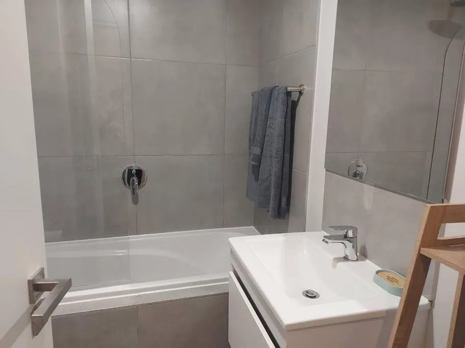 Modern bathroom with bathtub, shower enclosure, white sink and gray tiles