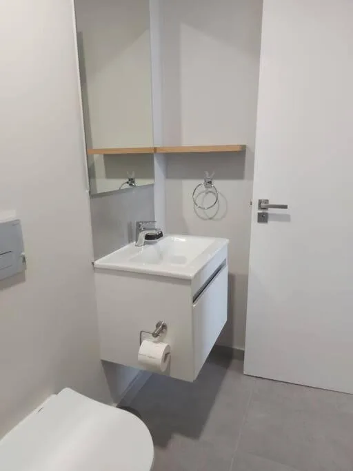 Modern bathroom with white vanity sink and wooden shelf above