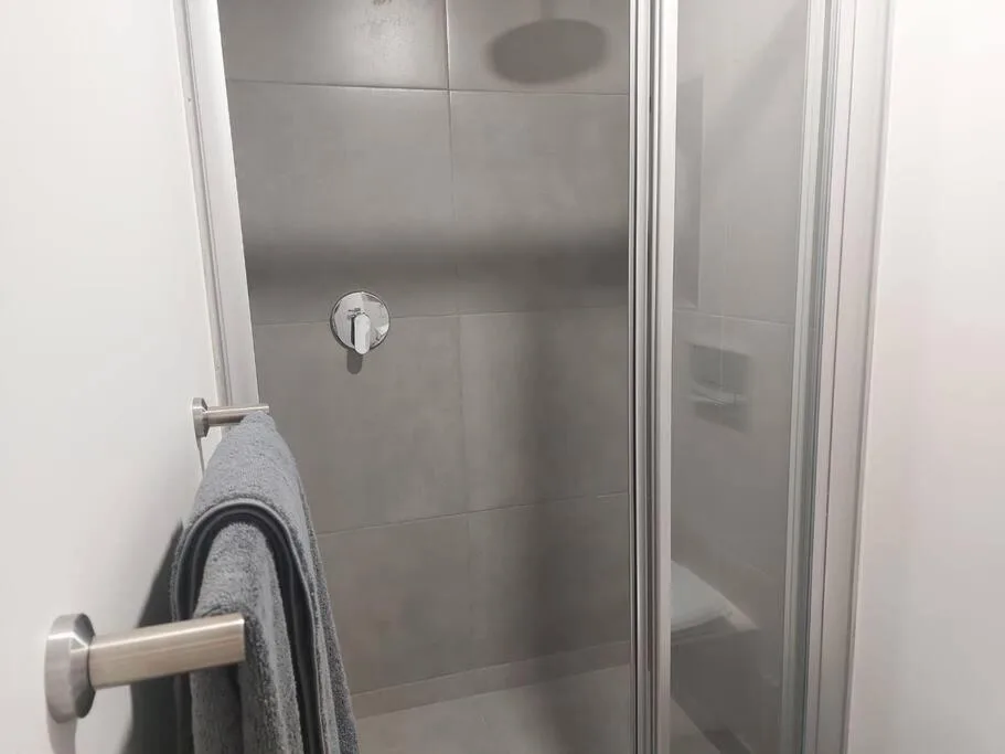 Modern shower enclosure with grey tile walls and chrome fixtures