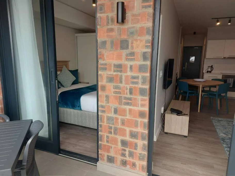 Modern bedroom with blue bedding visible through open brick partition doorway