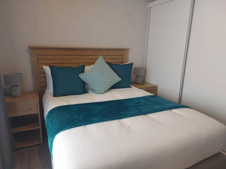 Modern bedroom with wooden headboard, teal bedding, and side table lamps