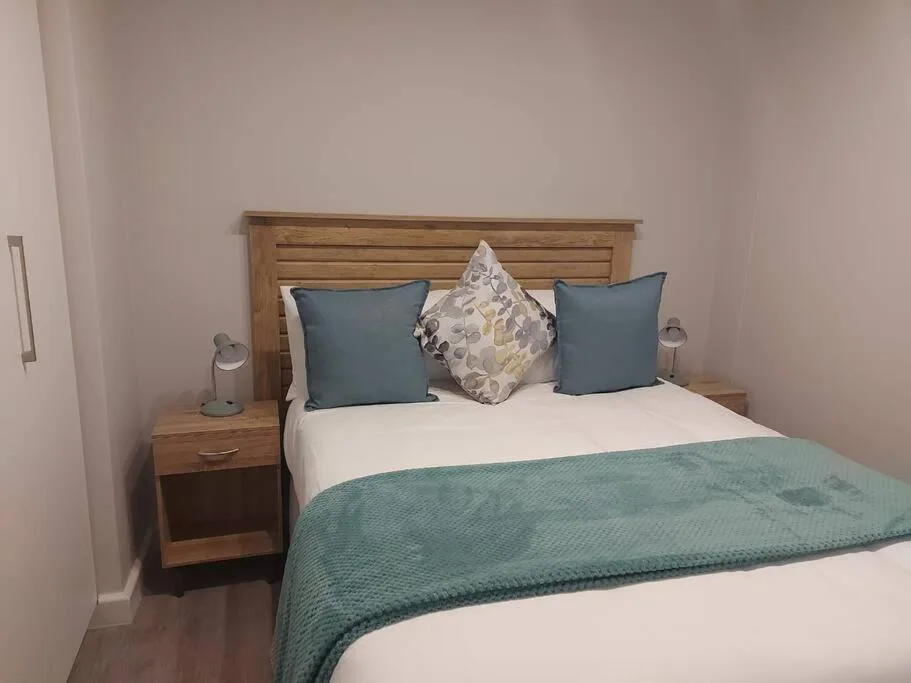 Neat bedroom with wooden bed frame, white linens, and blue accent pillows