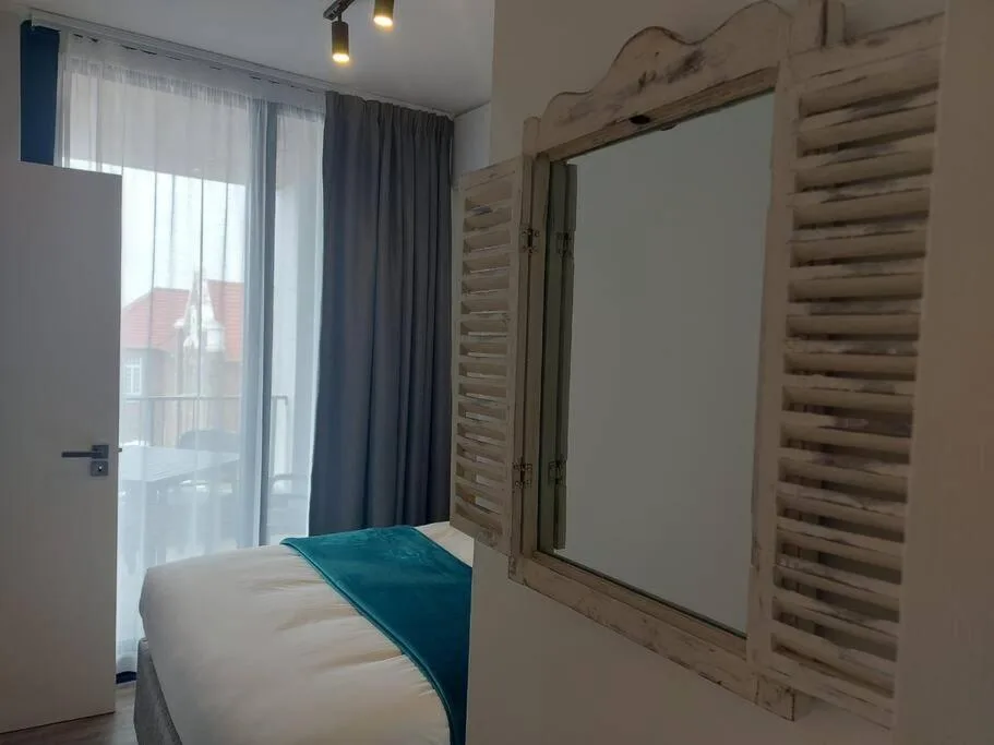Bright bedroom with bed, glass balcony doors, and rustic wooden wardrobe
