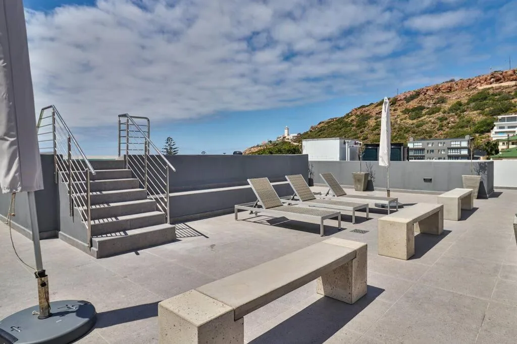 Rooftop terrace with loungers, seating, and hillside views