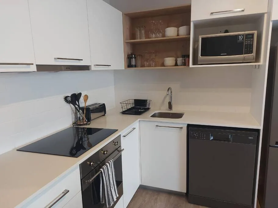 Modern kitchen with white cabinetry, black stovetop, and stainless steel appliances