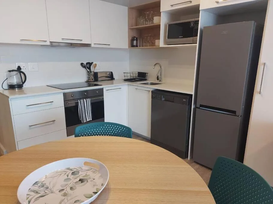 Modern kitchen with white cabinetry, stainless steel appliances, and dining table