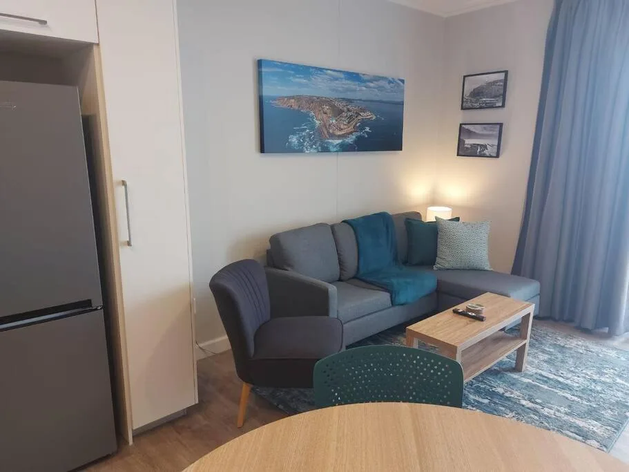 Modern living room with gray sofa, blue accents, and coastal artwork on walls