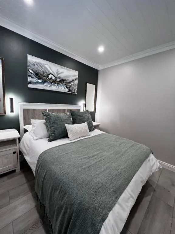 Modern bedroom with queen bed, dark accent wall, and contemporary artwork