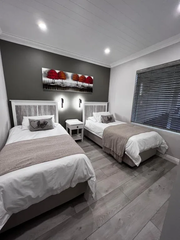 Twin bedroom with white bedding, dark accent wall, and modern lighting