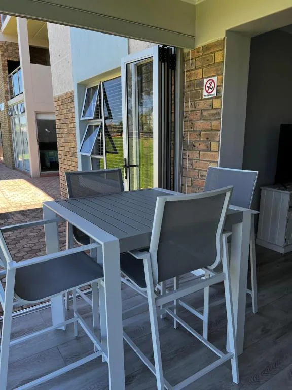 Modern outdoor patio with dining table and chairs overlooking garden