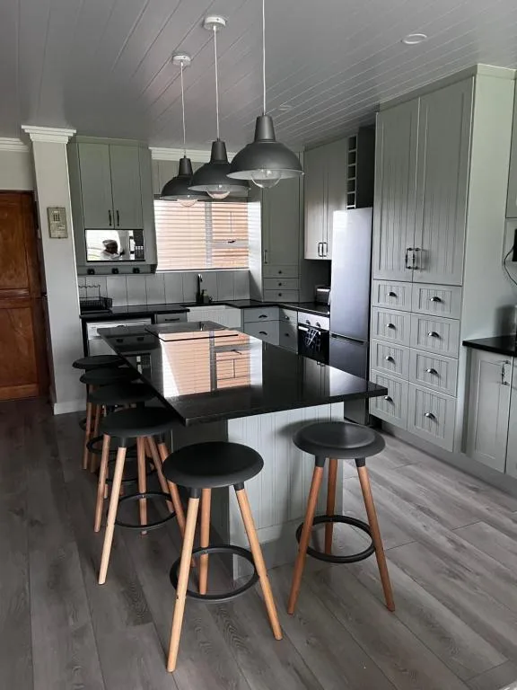 Modern kitchen with island, black countertops, pendant lights, and bar seating