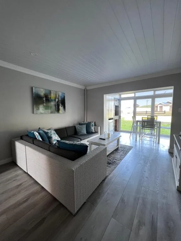 Modern living room with black sofa, glass doors opening to deck view